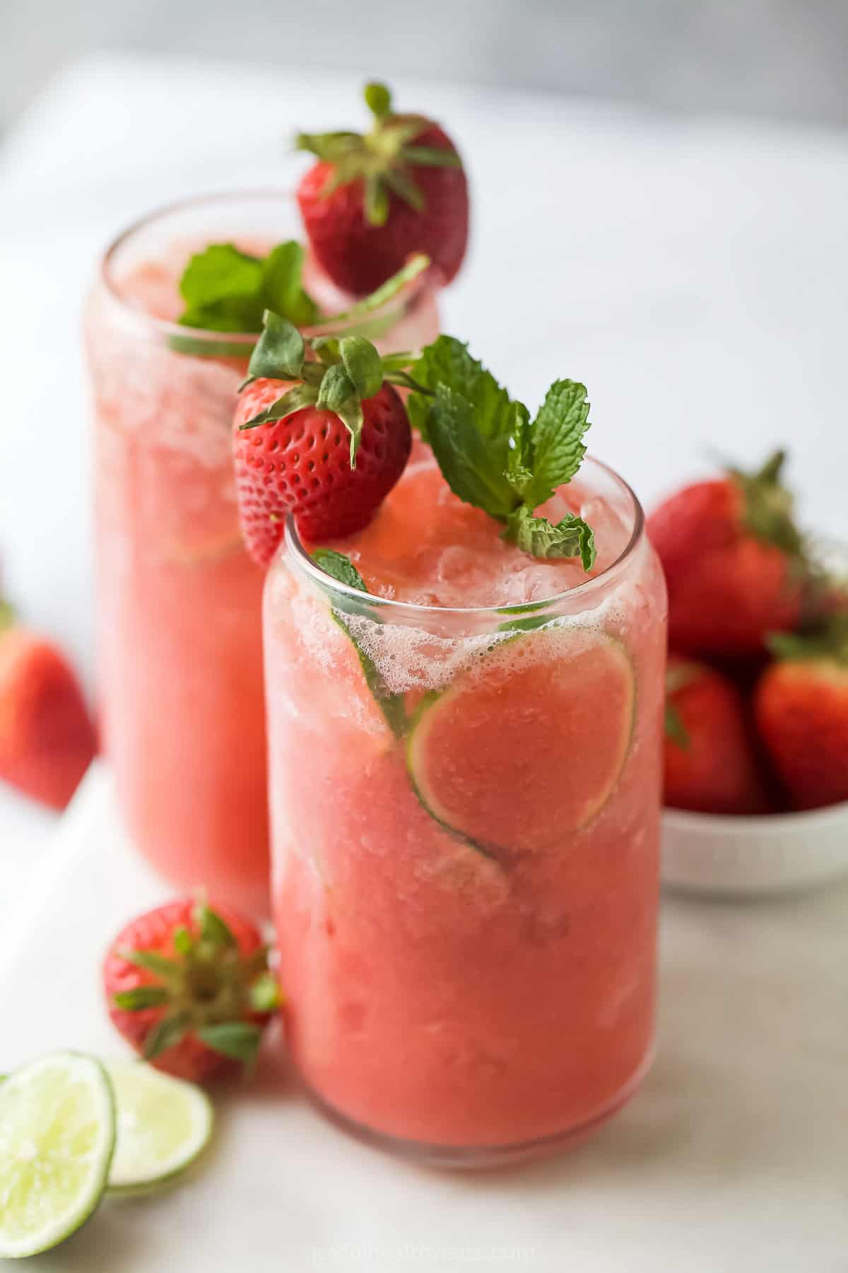 This fruity strawberry limeade recipe with agave nectar is a fizzy, 5-minute drink you'll be making all summer. Strawberry limeade in a glass with mint and strawberry garnishes.