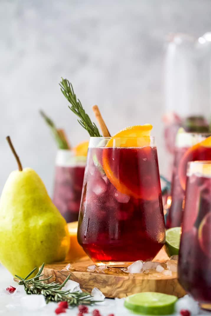 This easy Christmas holiday sangria is filled with citrus, pomegranate, pear & cinnamon. It's totally delicious and the BEST winter sangria! the ultimate holiday sangria recipe in a glass with ice and garnishes