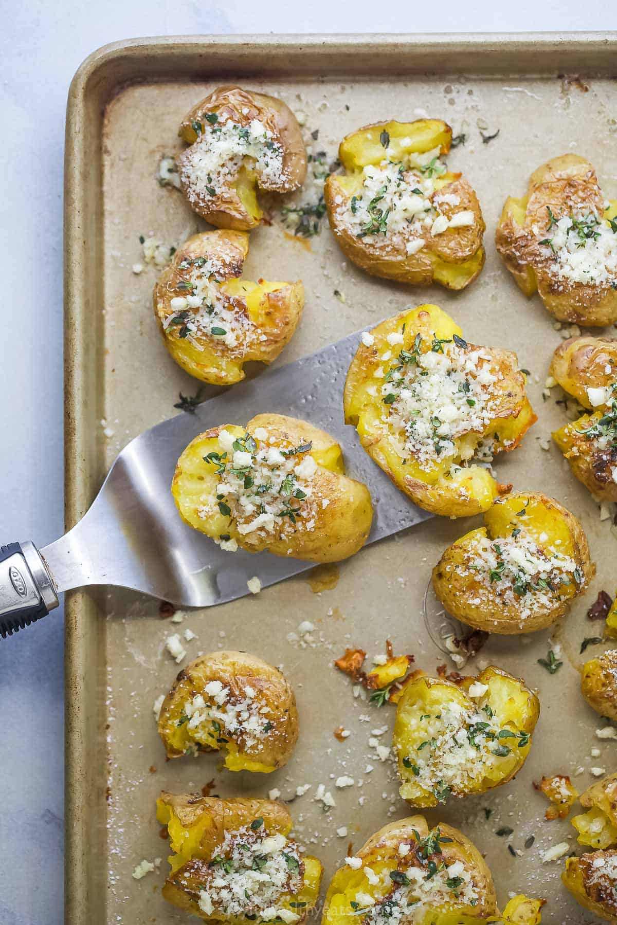 Crispy baby potato with garlic-herb mixture on a spatula. 
