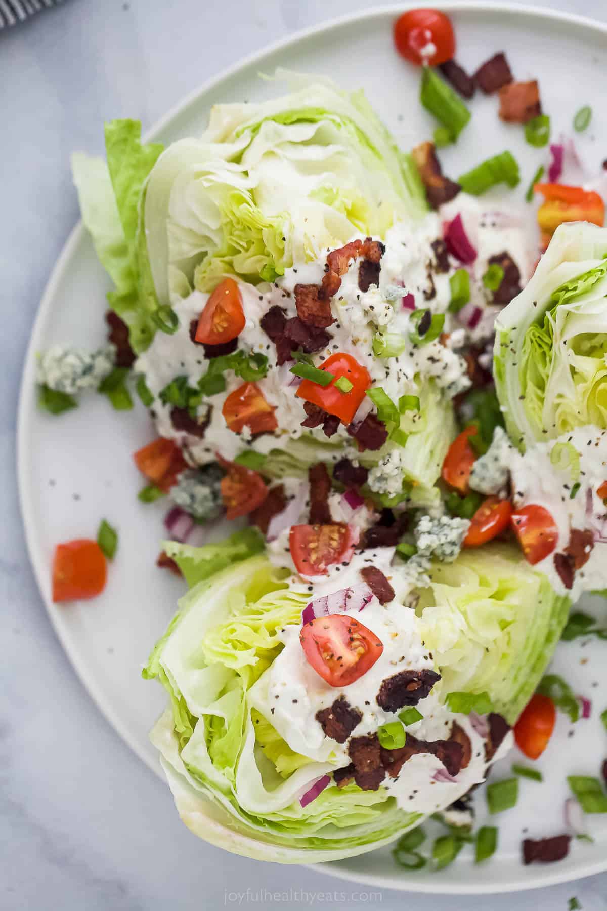 This Classic Wedge Salad with Blue Cheese Dressing is loaded with flavor from the crispy Bacon to the tangy dressing. It's light and easy! Wedge Salad with iceberg lettuce, tomatoes, bacon, red onions and creamy dressing
