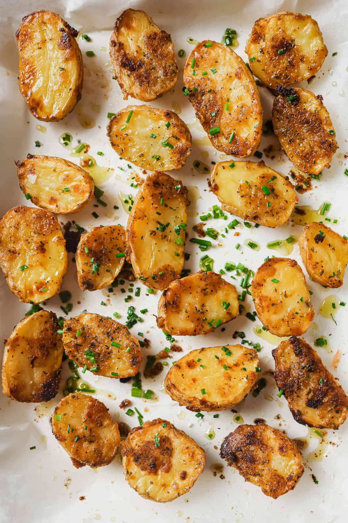 These garlic ranch potatoes are an easy baked side that'll make everyone happy with their crispy exterior and buttery center. Garlic ranch potatoes in the baking tray sprinkled with parsley.