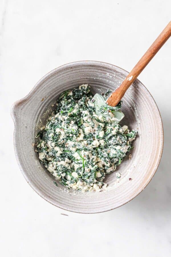 Stirring the cottage cheese, spinach, onion, and garlic filling in a bowl. 