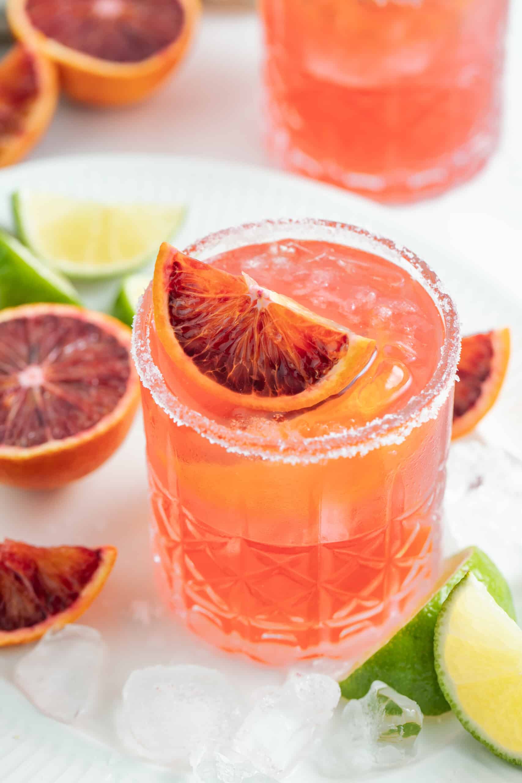This Fresh Blood Orange Margarita Recipe is festive, citrusy, and flavorful. Plus, it's easy to make and doesn't include simple syrup! an ruby red colored margarita with blood orange garnish