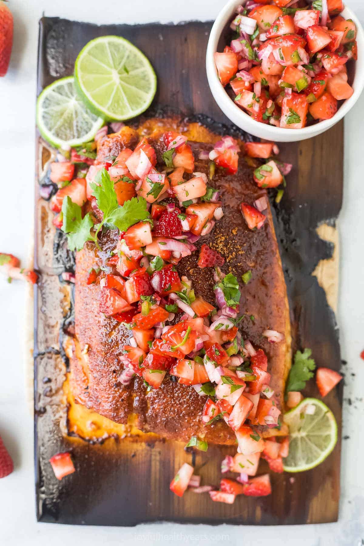 This 25-minute cedar plank salmon with strawberry salsa is flaky, spiced, smokey, and fruity all in one bite. It's perfect for the summer! Cedar plank salmon with strawberry salsa.
