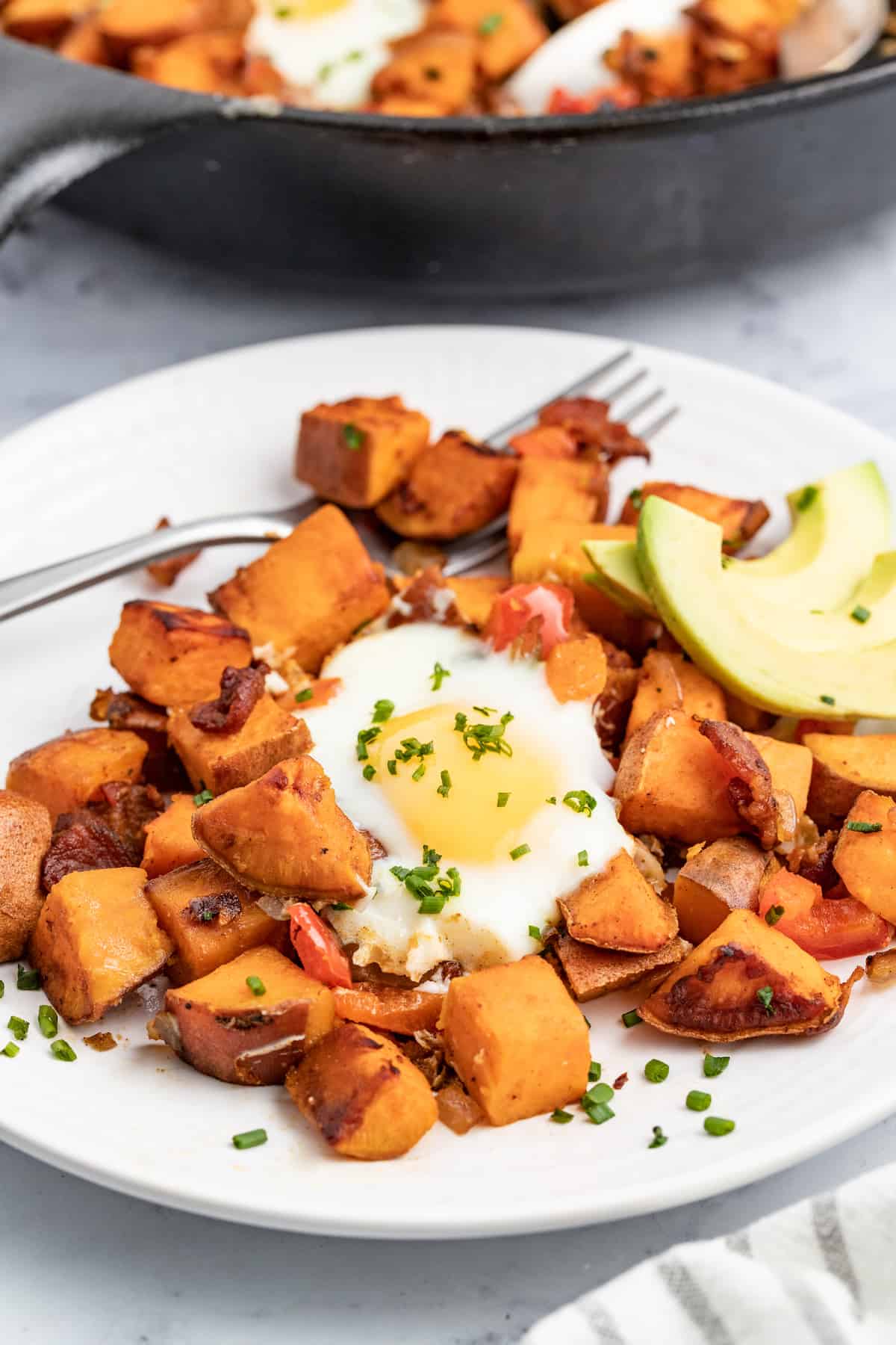 This sweet potato hash is packed paprika, crispy bacon, and eggs for the perfect sweet and savory breakfast bite. Sweet potato hash with an egg and avocado.