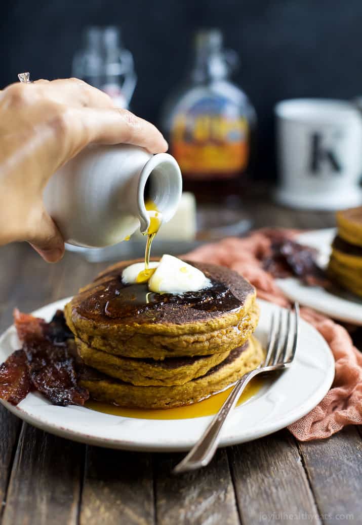 These fluffy whole wheat pumpkin pancakes are full of warm fall spices and served with crispy, sweet-and-salty candied bacon! So good. Pumpkin pancakes topped with two pats of butter and a drizzle of pure maple syrup.