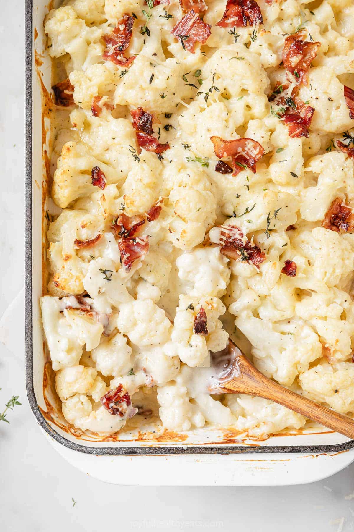 This creamy cauliflower au gratin recipe with crispy bacon, thyme, and homemade cheese sauce is an easy, veggie-packed holiday side. Freshly baked cheesy cauliflower au gratin with bacon.
