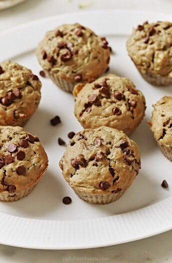 Freshly baked zucchini chocolate chip muffins on a serving plate.