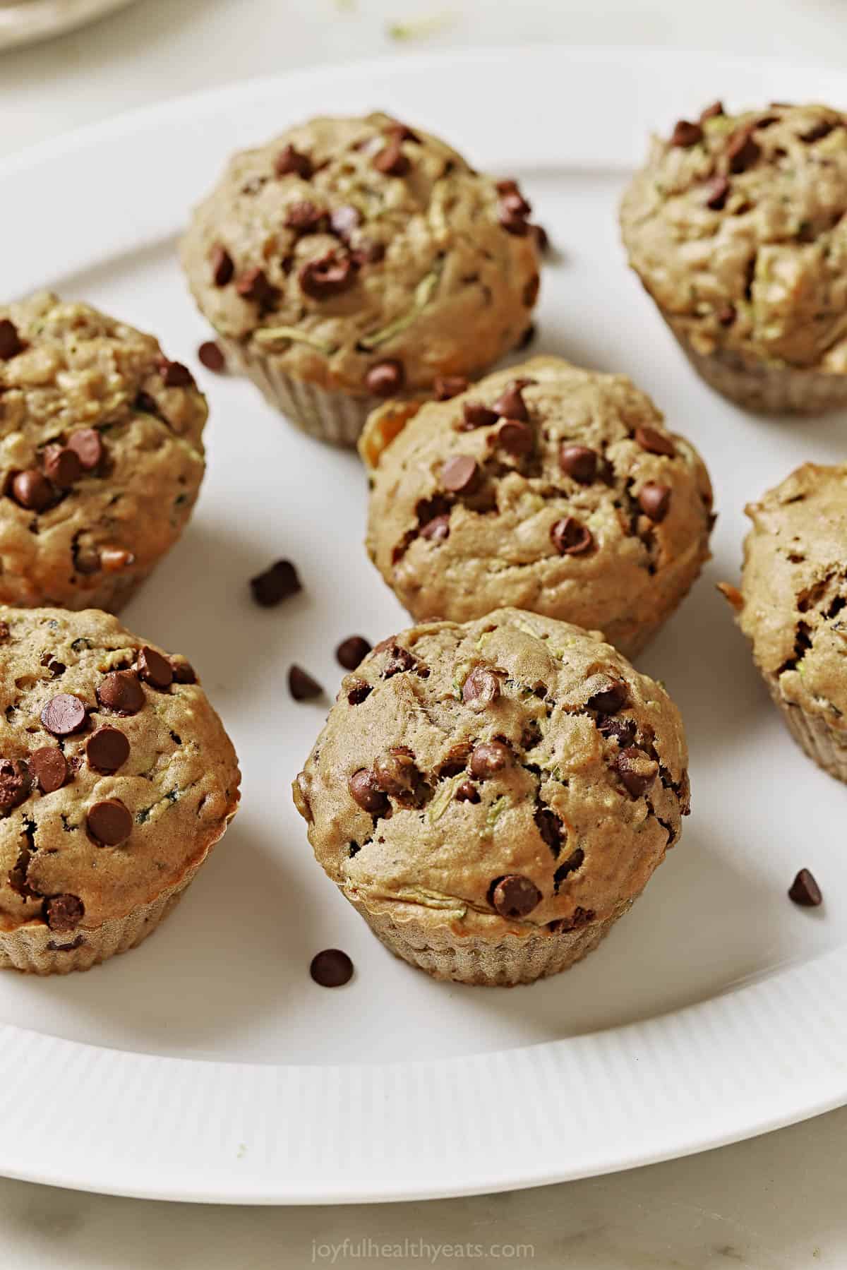 This naturally-sweetened zucchini chocolate chip muffins recipe Freshly baked zucchini chocolate chip muffins on a serving plate.
