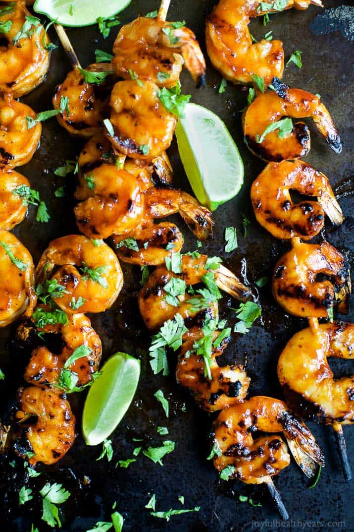 Crusted with a sweet and spicy honey sriracha glaze, these Honey Sriracha Shrimp are downright heavenly! They're majorly juicy & flavorful. Honey sriracha grilled shrimp garnished with chopped parsley and fresh lime slices
