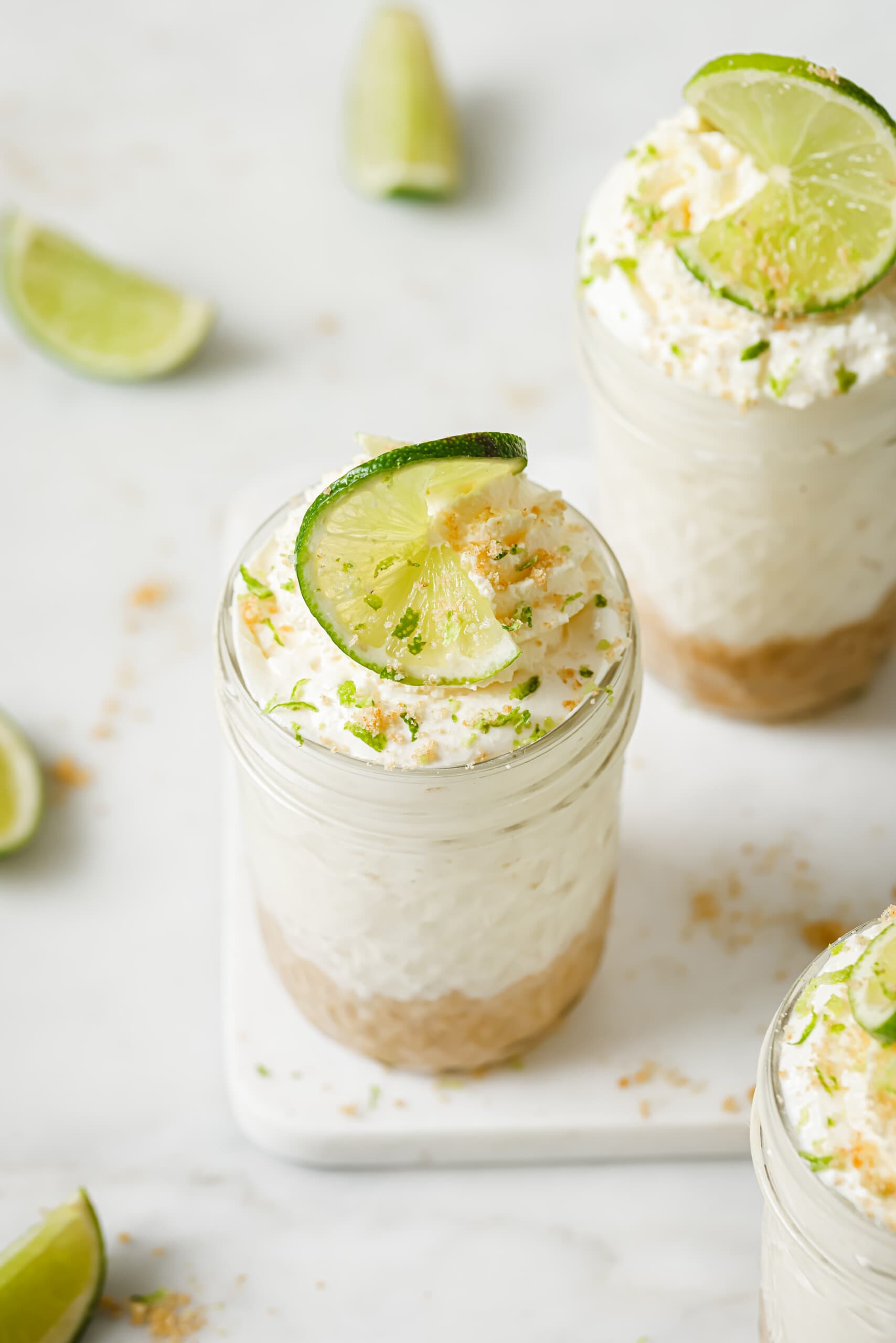 This easy no-bake key lime cheesecake with a buttery homemade crust is the perfect on-the-go treat for the summer. Angled photo of key lime cheesecake in a jar with whipped cream on top.