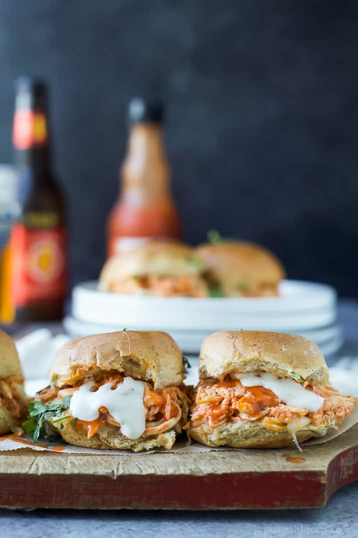 These Buffalo Chicken Sliders are made in less than 30 minutes with only 5 ingredients! Easy to prep & perfect for game day! Two buffalo chicken sliders on a cutting board