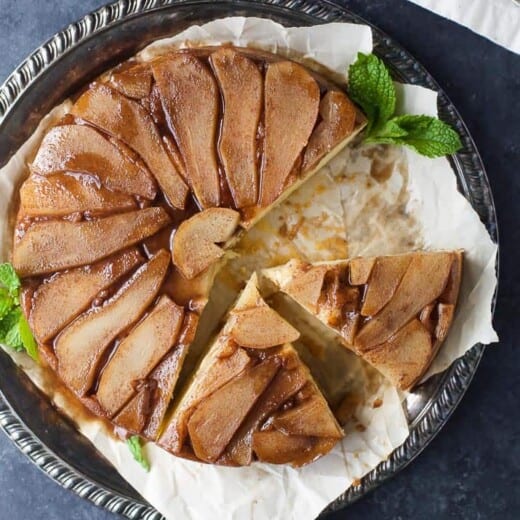 A homemade, sliced pear upside down cake on a serving plate.