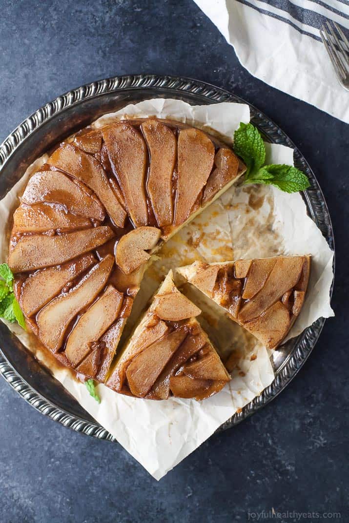 This tender pear upside down cake recipe with homemade spiced caramel is a fancy-but-easy dessert for the holidays. A homemade sliced pear upside down cake on a serving plate.