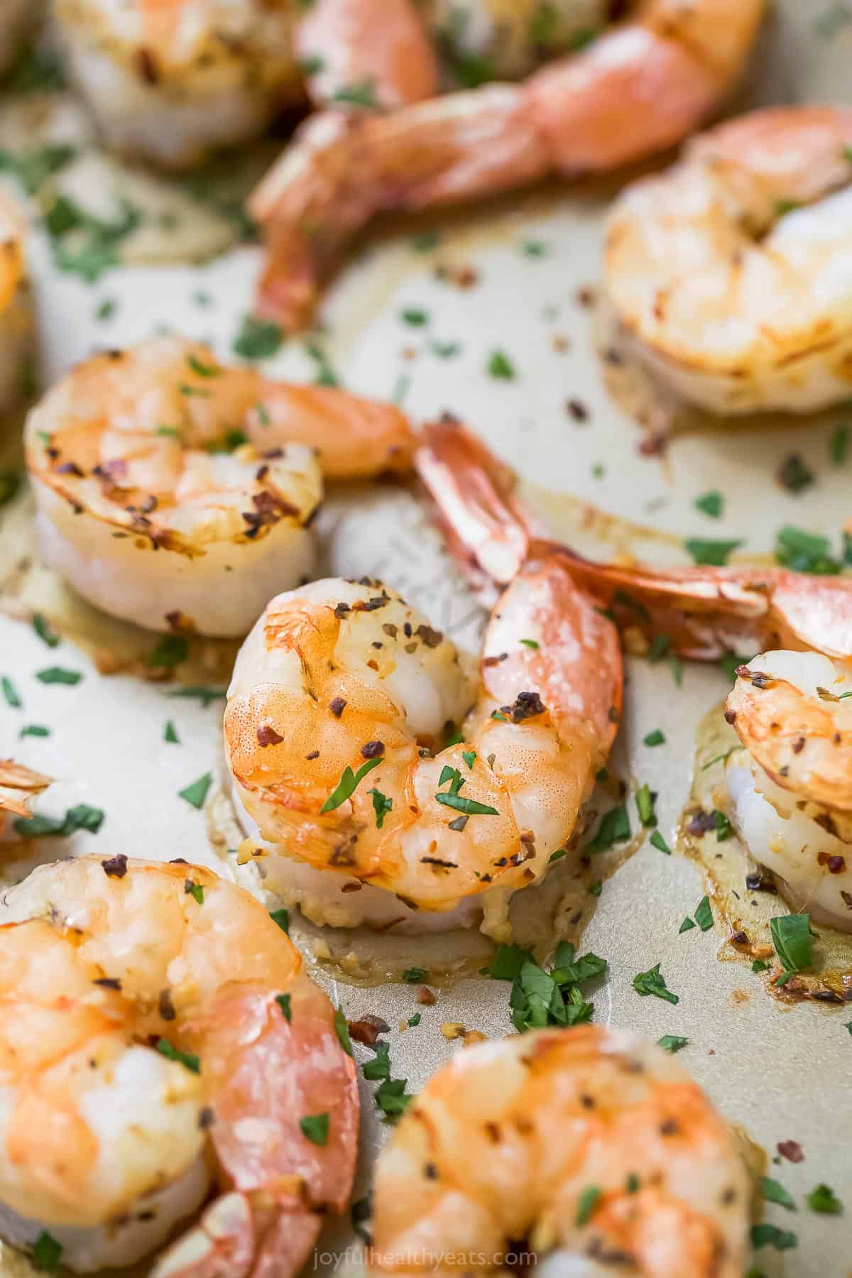 These roasted shrimp are packed with garlic and spicy red pepper flakes for the ultimate bite when dipped into their sweet cocktail sauce. Roasted shrimp in the baking sheet.