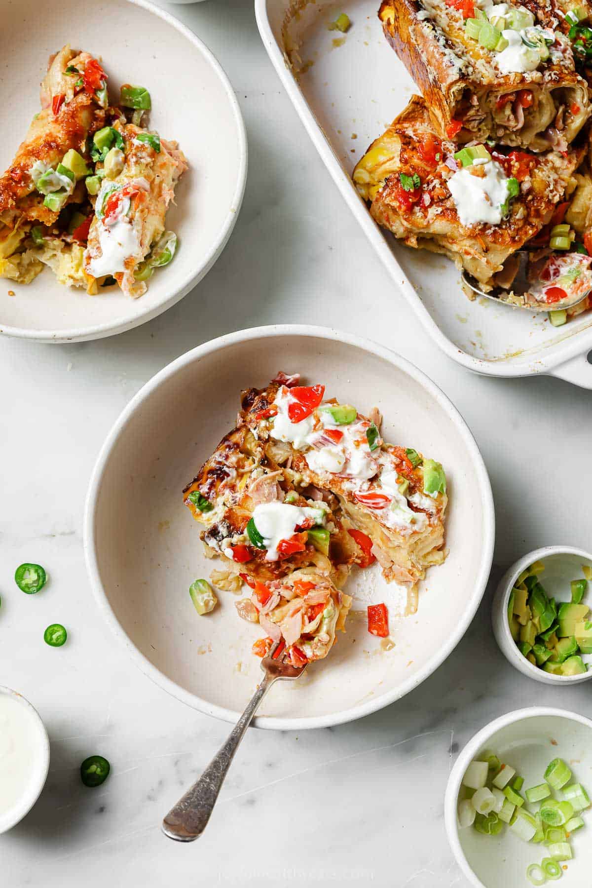 Breakfast enchiladas in a serving plate with toppings. 