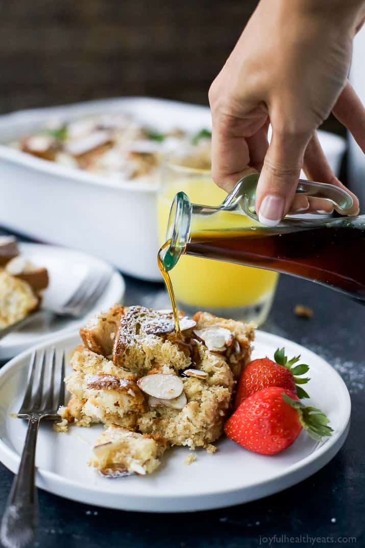 Eggnog French toast casserole is an easy make-ahead holiday breakfast. It's filled with festive spices and a great way to use up eggnog! Maple syrup being poured over a serving of French toast casserole on a plate