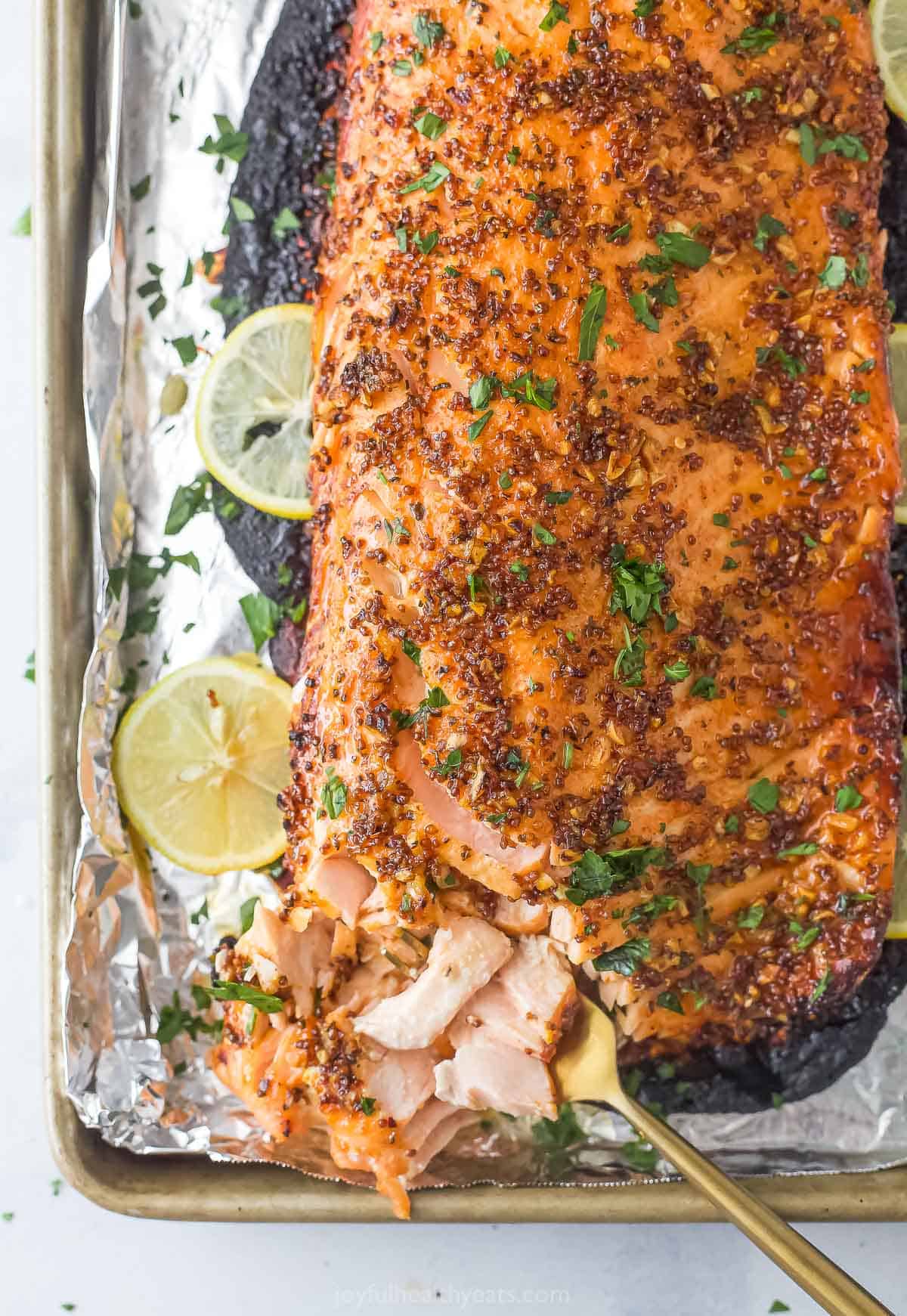 This quick honey mustard salmon recipe is an easy clean-up dinner with hints of garlic, spicy red pepper flakes, and tangy lemon juice. Honey mustard salmon with fresh parsley on top.