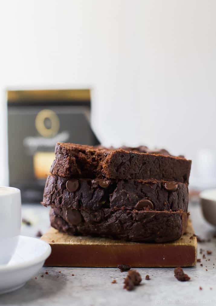 This tender chocolate zucchini bread recipe with maple syrup, applesauce, and dark chocolate chips will be your new favorite breakfast. Stack of chocolate zucchini bread slices.