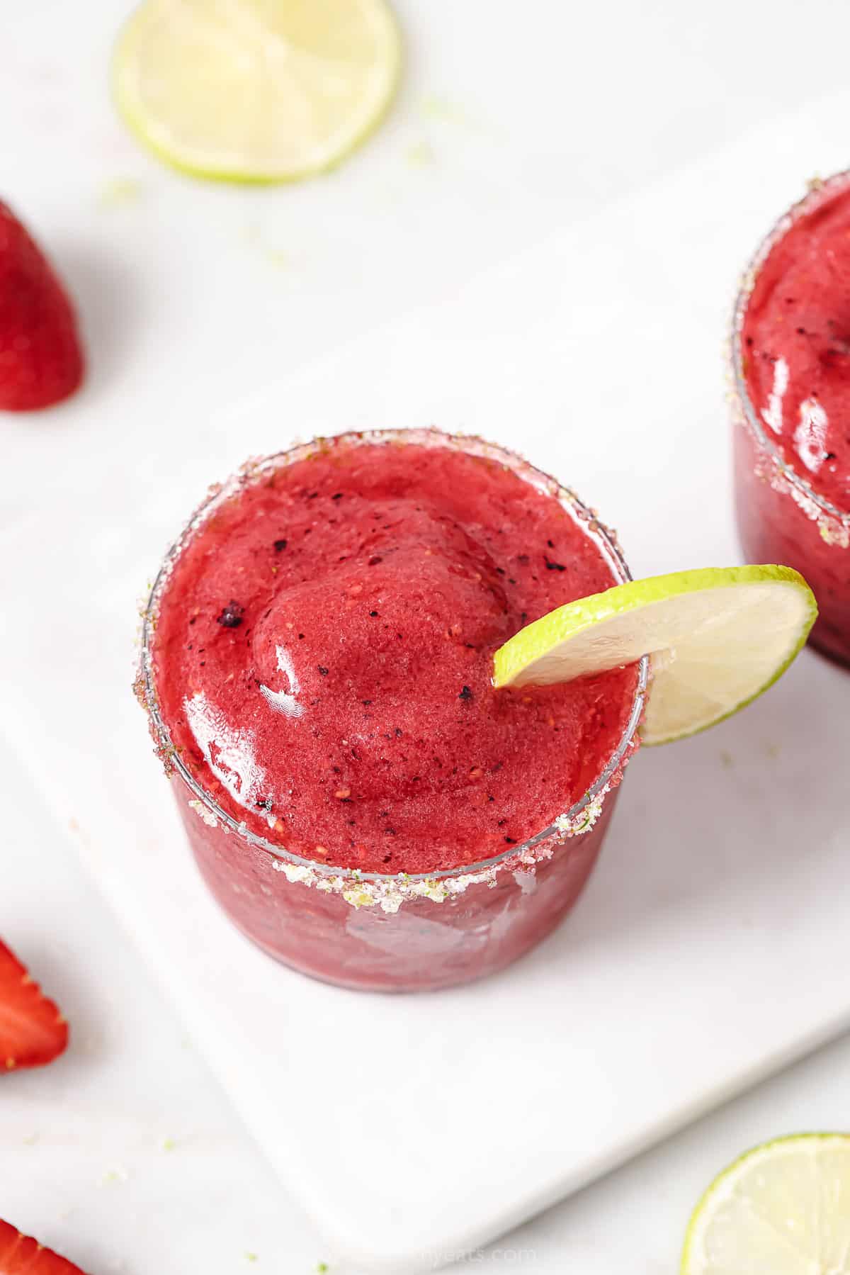 Close-up of a frozen berry cocktail with a lime-sugar rim and lime wedge. 