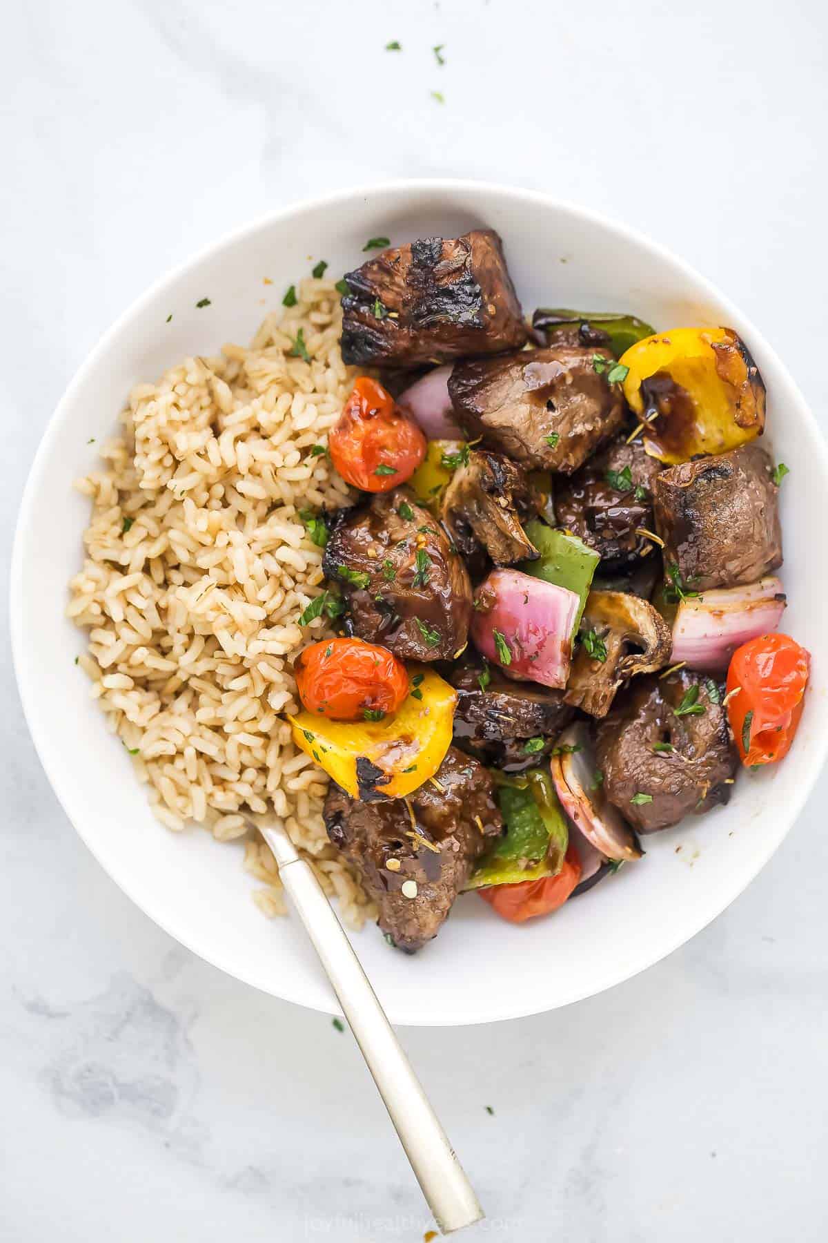 Cooked beef and veggies in a bowl with rice. 