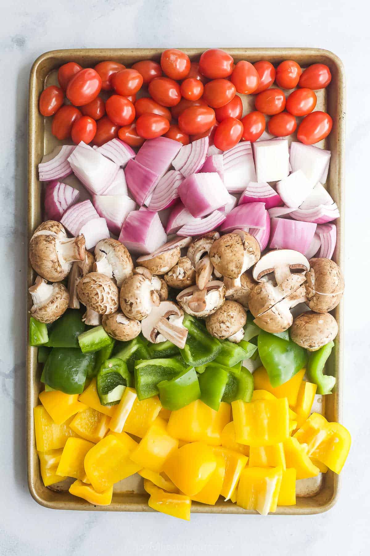 Chopped veggies for beef kabobs on a baking sheet. 