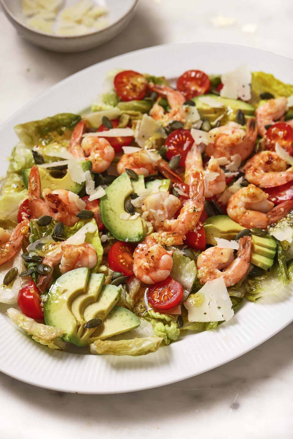 This grilled shrimp caesar salad recipe with homemade parmesan dressing, creamy avocado, and tomatoes is a light 15-minute lunch. Shrimp caesar salad with grilled lettuce, avocado, tomatoes, and homemade dressing.