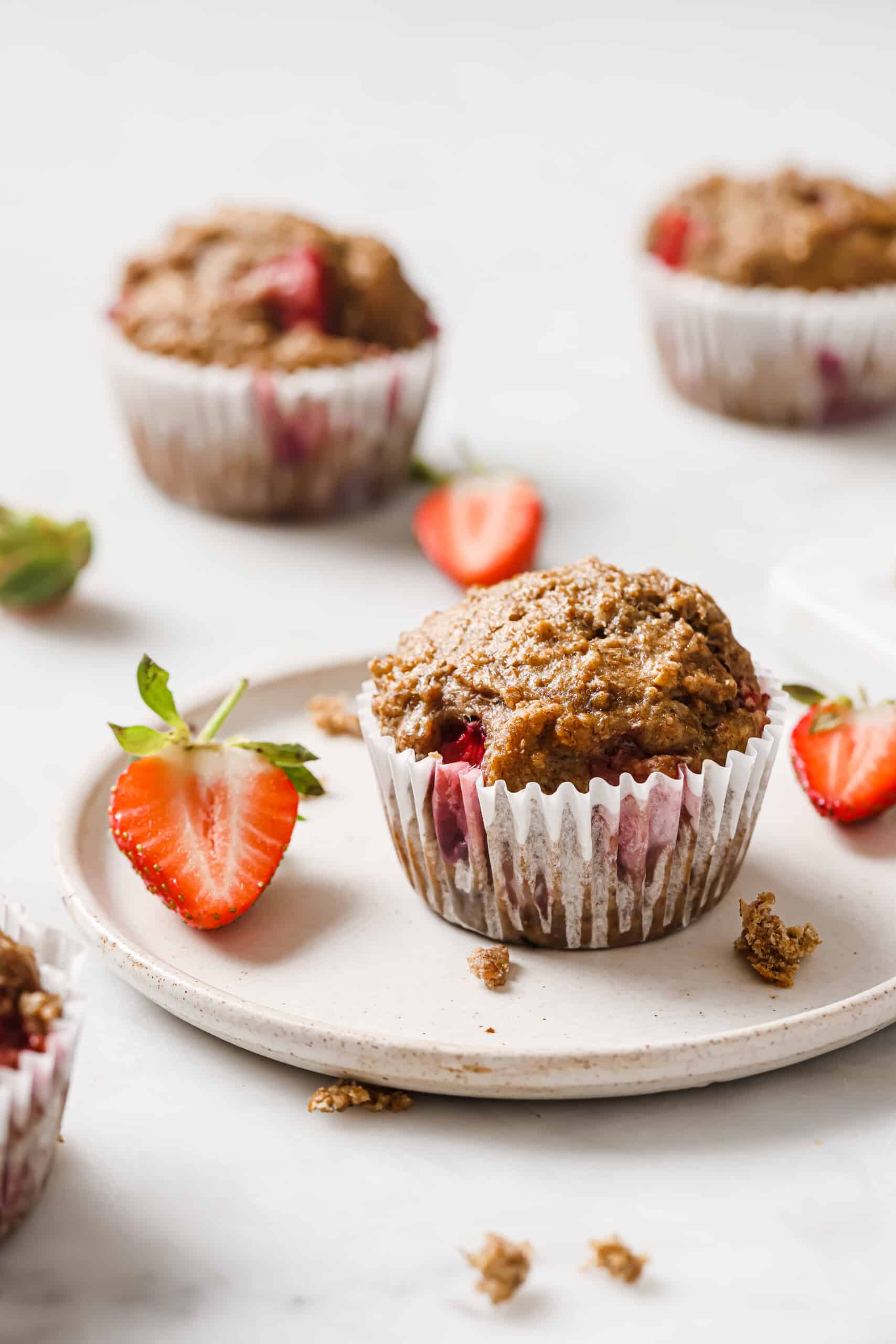 These moist strawberry muffins are a healthy dessert turned breakfast. They're ready in less than 30 minutes and are great for the week. A strawberry muffin on a plate.