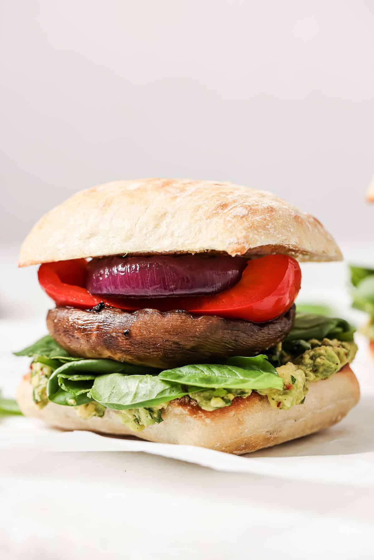 This grilled portobello mushroom burger recipe with spicy cilantro chimichurri is a 30-minute lunch that's perfect for summer. Close-up of portobello mushroom burger in a ciabatta bun.