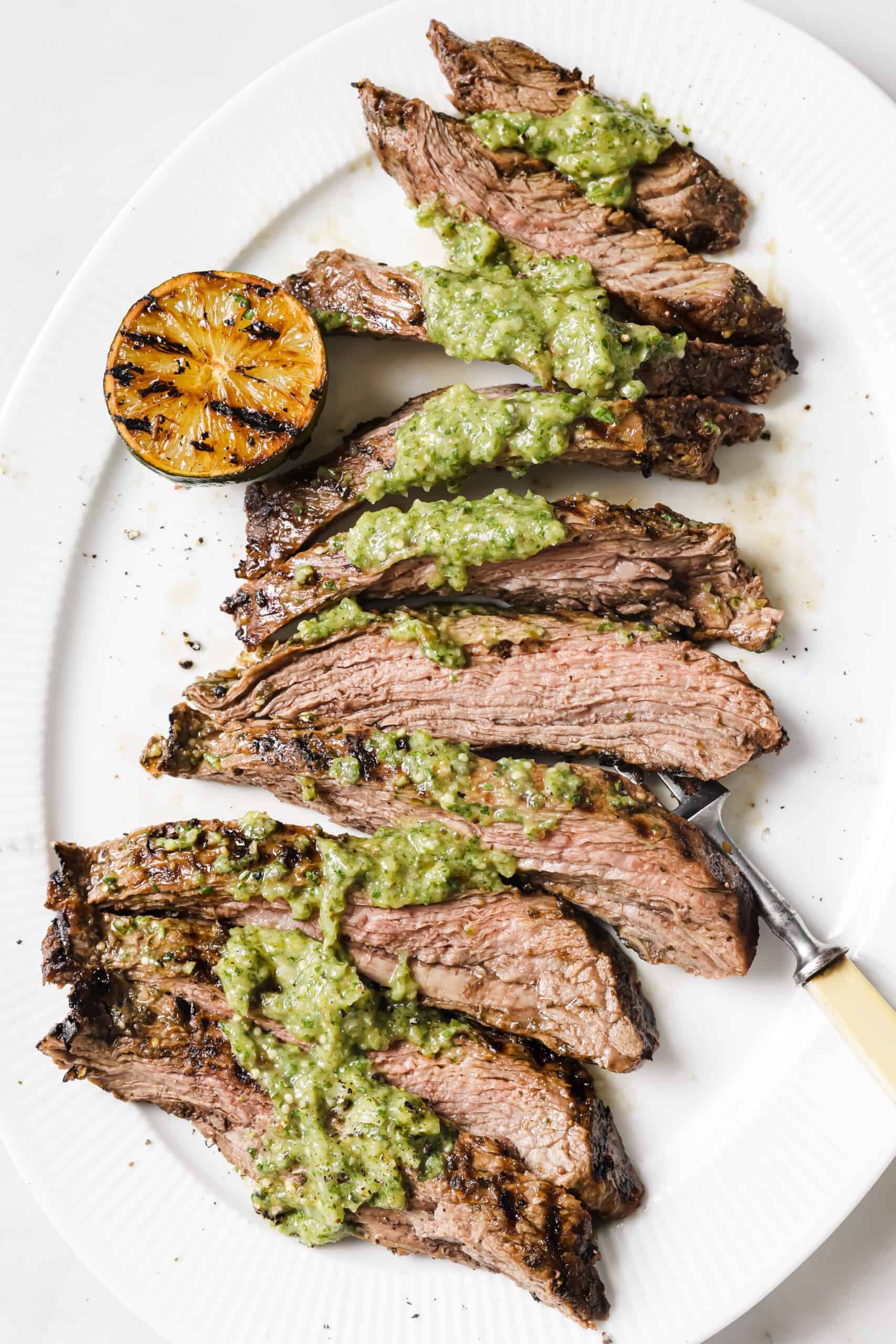 This easy carne asada recipe with salsa verde will be your new favorite Mexican dinner. Easy to make and super juicy, it's the perfect dish! Grilled carne asada recipe with salsa verde on top.