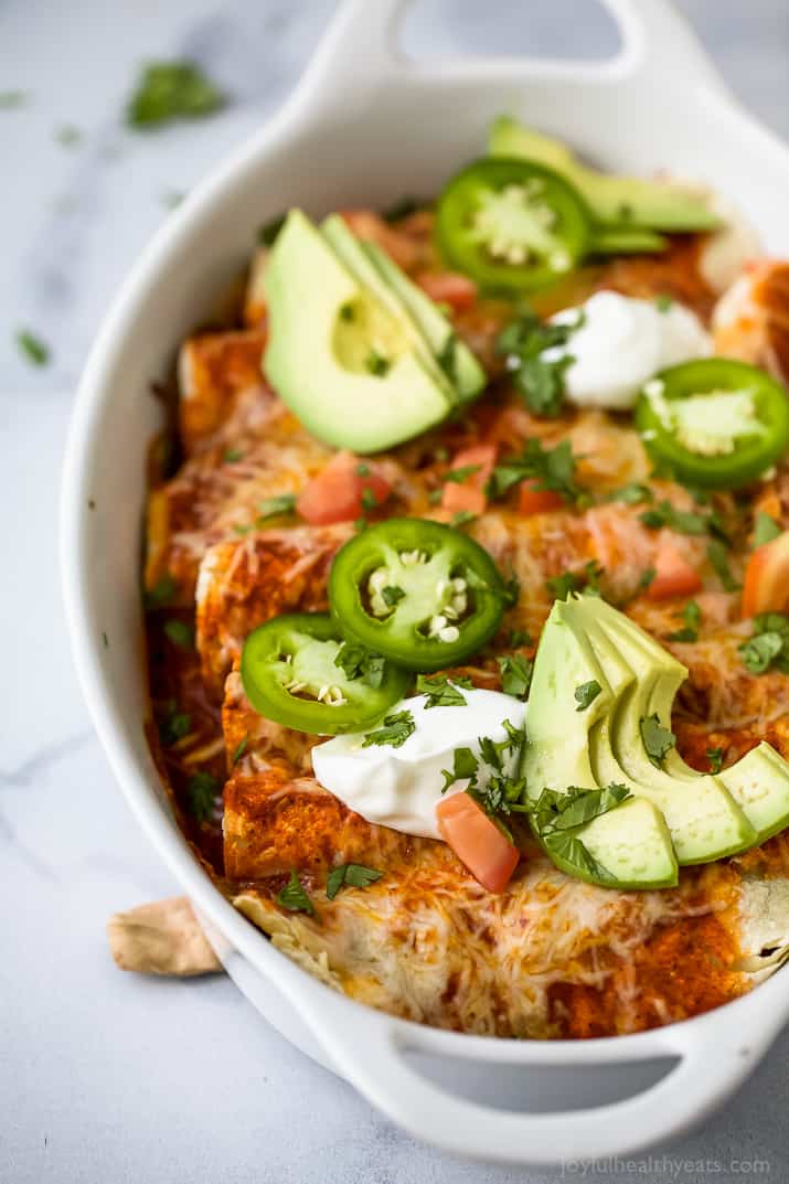 This saucy sweet potato black bean enchiladas recipe with smokey seasonings, spicy salsa, and melty cheese is an easy Tex-Mex dinner. Sweet potato black bean enchiladas with jalapeños, sour cream, and diced avocado on top.