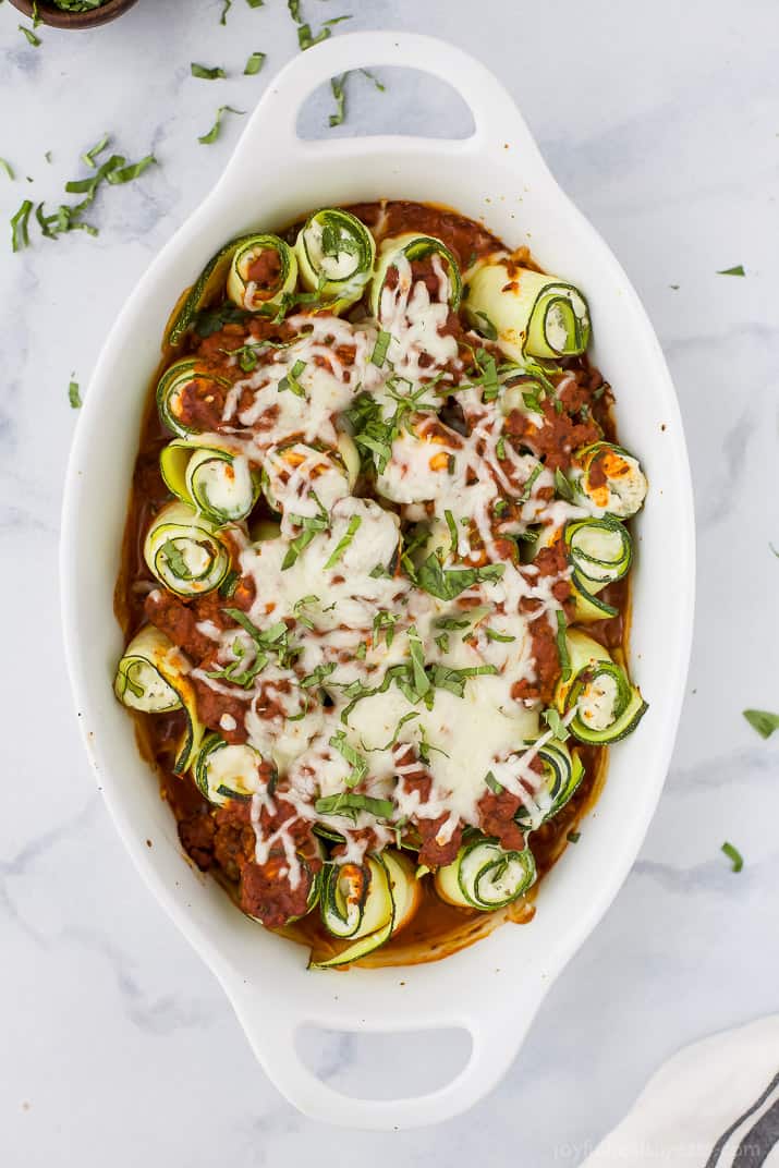Zucchini rolls with melty cheese on top, in the baking dish.