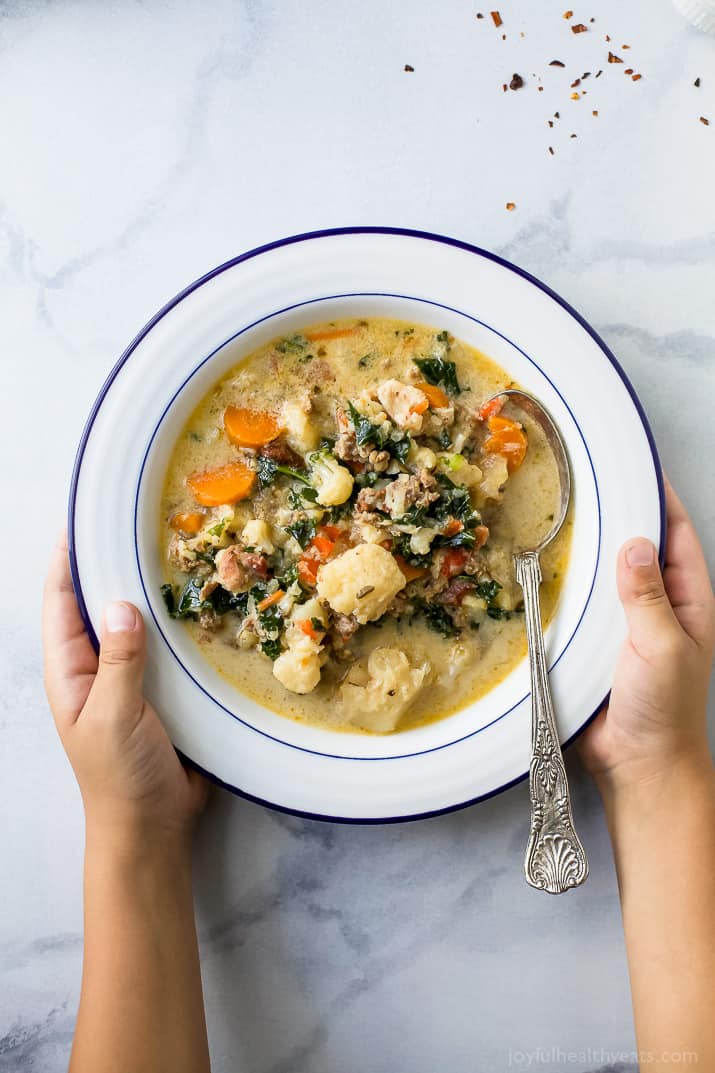 Holding onto a bowl of creamy zuppa toscana with sausage, bacon, and veggies. 