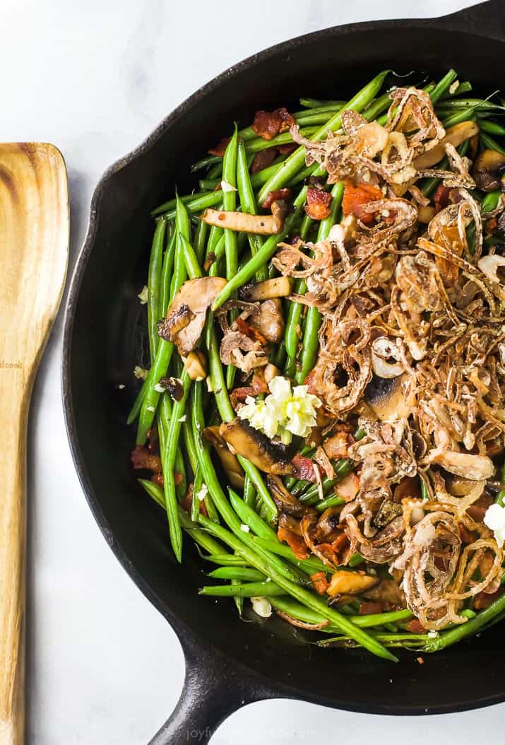 Healthy green bean casserole in a skillet near a wooden spoon.