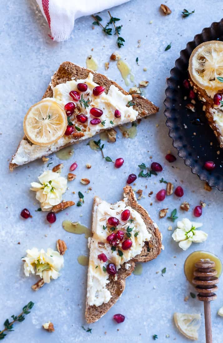 Overhead photo of creamy ricotta cheese toast with tart pomegranate, pecans, and honey. 