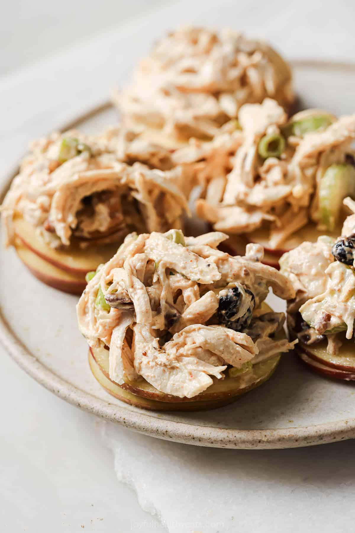 This 15-minute cranberry chicken salad recipe is a creamy, hearty lunch option for the week filled with pecans and celery. Cranberry chicken salad over sliced apples.