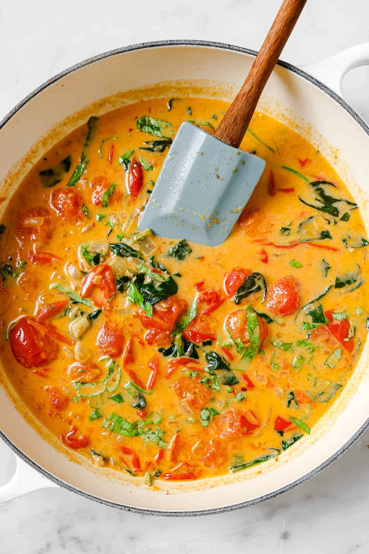 Stirring the coconut milk into the pan to make the sauce. 
