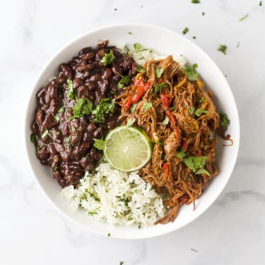 crock pot ropa vieja recipe (cuban shredded beef) in a bowl with rice and beans