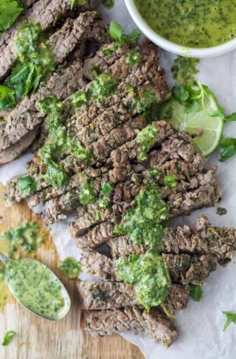 the best marinated grilled flank steak on a cutting board with chimichurri sauce