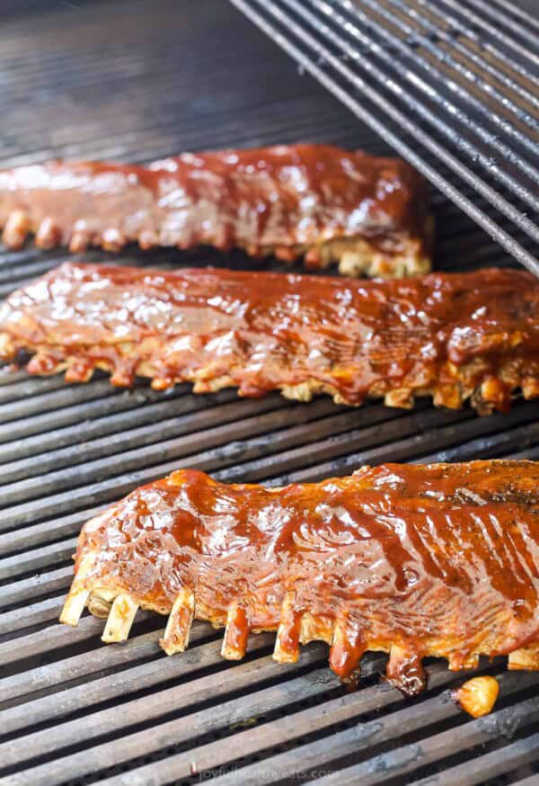Baked ribs on the grill with BBQ sauce brushed on top. 