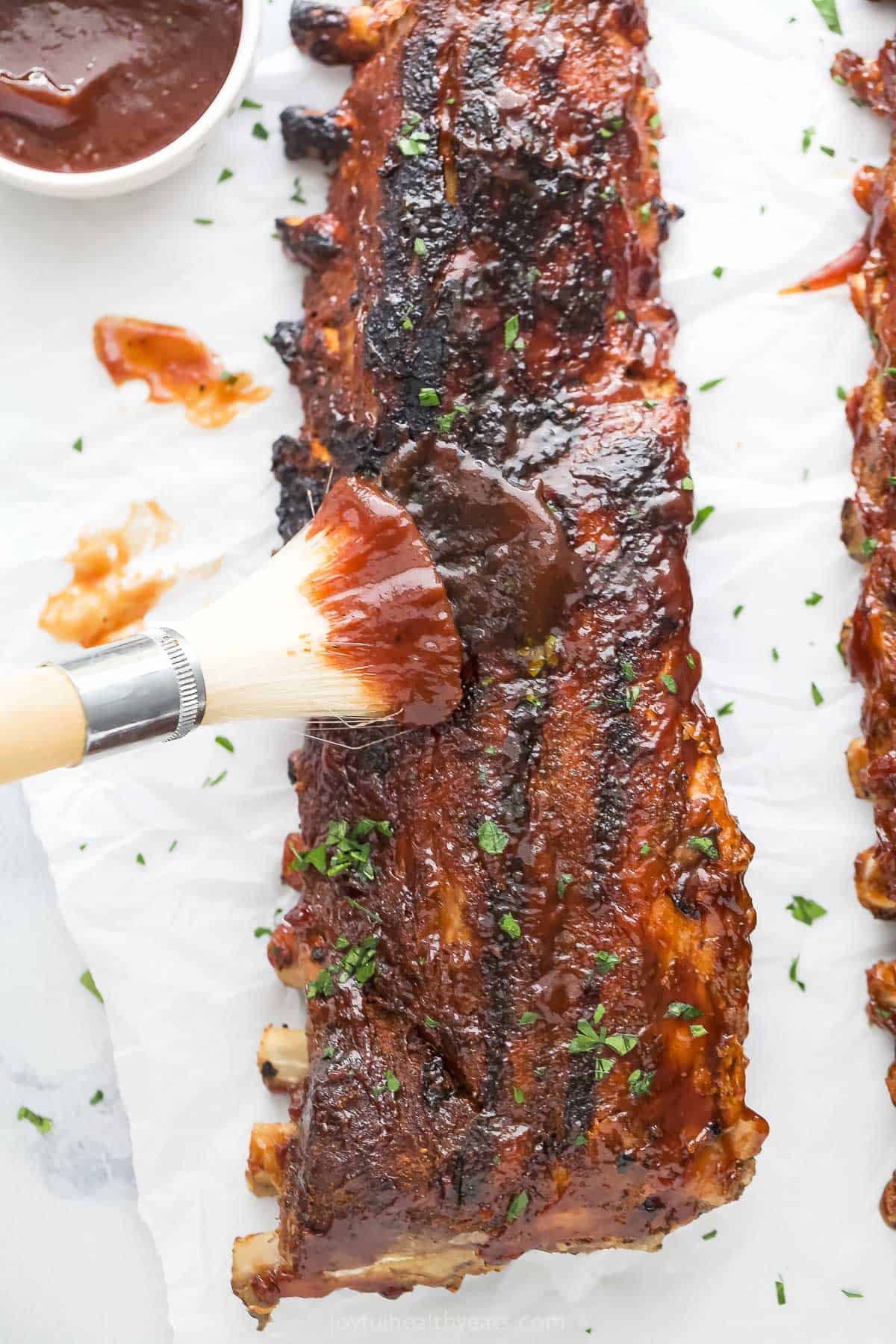 Brushing more BBQ sauce on the grilled ribs. 