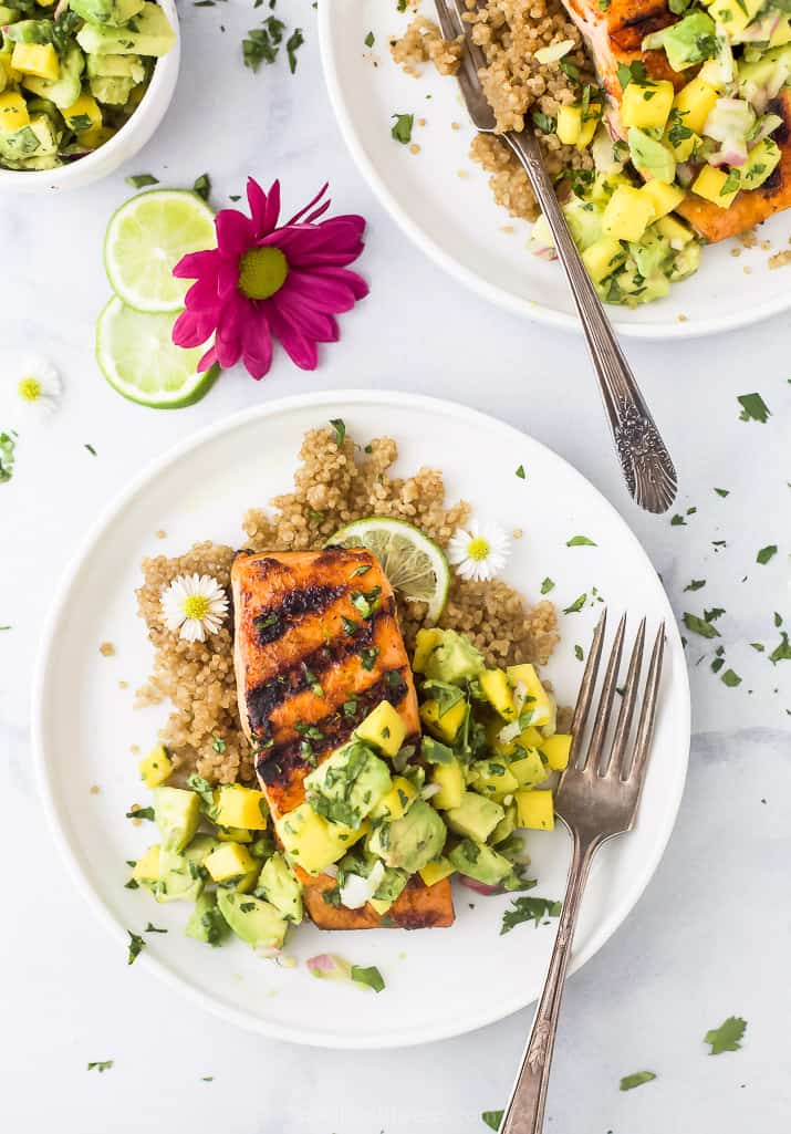 Chili lime salmon topped with mango avocado salsa is perfect for summer! This grilled salmon is so flaky and tender, and so easy to make. chili lime grilled salmon with mango avocado salsa on a plate with a fork