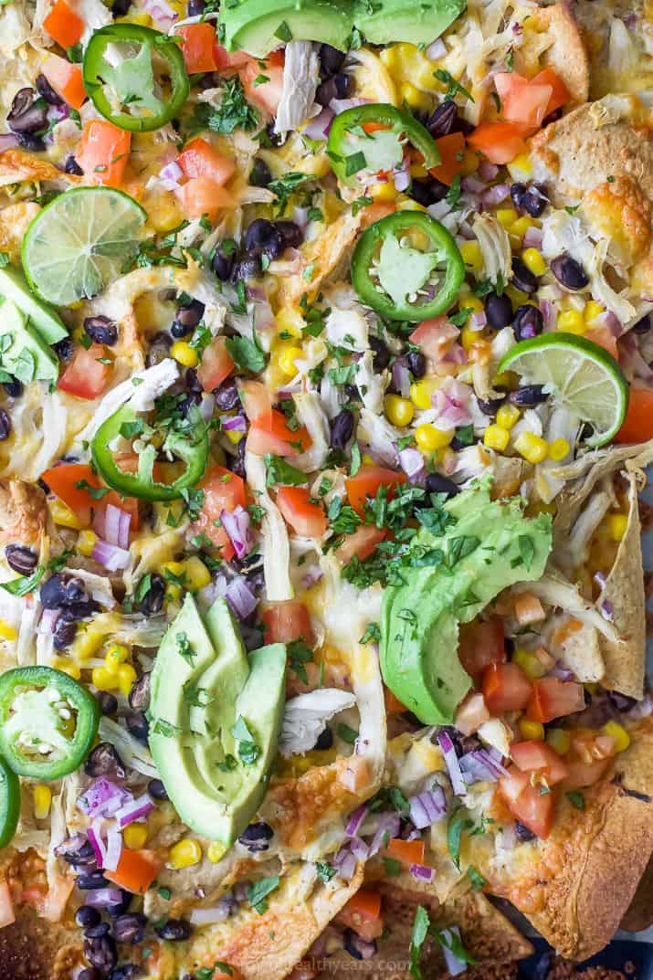 overhead photo of easy 20 minute sheet pan chicken nachos topped with avocado