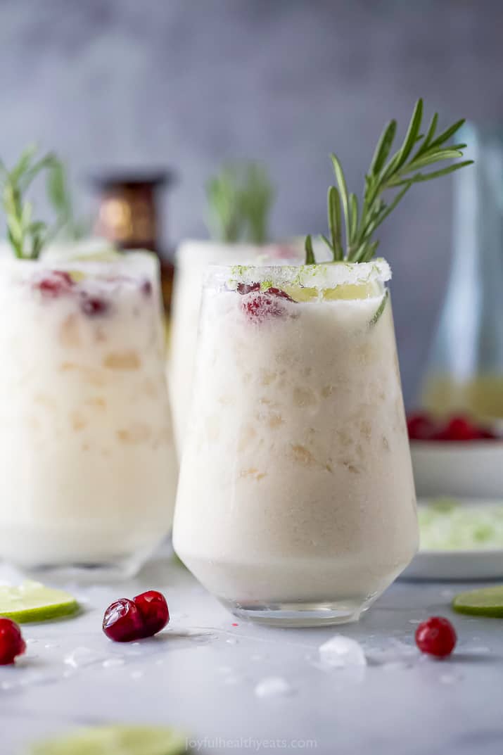 A White Christmas Margarita Pitcher Recipe that tastes like Christmas in a cup with tequila. Guaranteed to be a hit at your holiday party! white christmas margarita recipe in a glass with cranberries and rosemary