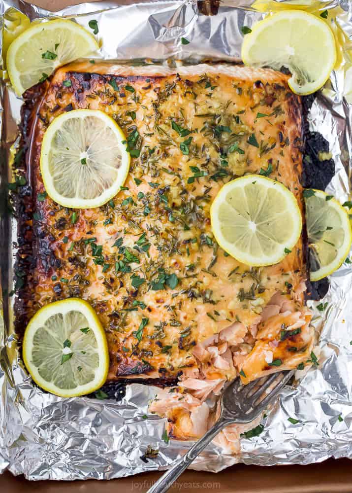 Baked honey garlic salmon in foil is the easiest dinner recipe. Flaky salmon is coated in a tangy honey garlic sauce and baked until crispy! Baked honey garlic salmon in foil with a fork.