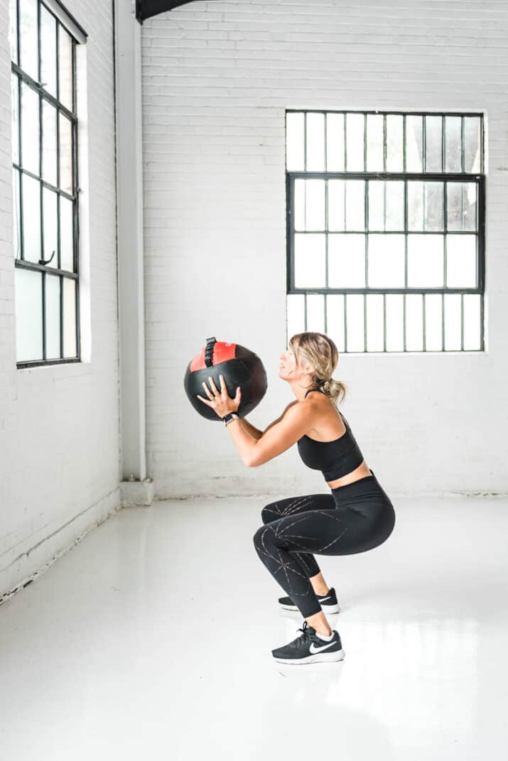 girl doing a squat with a wall ball