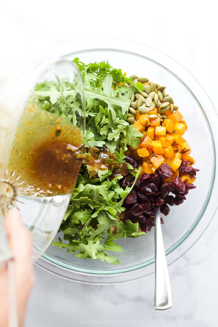 Pouring dressing into the farro salad ingredients.