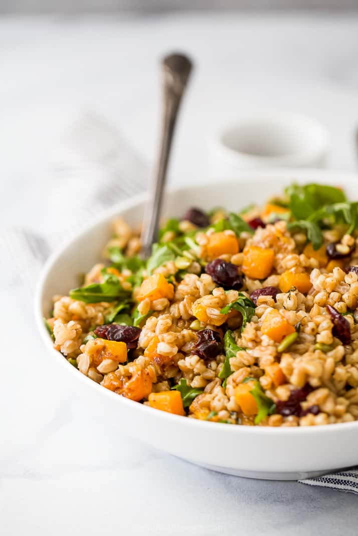 Farro salad with cranberries, arugula, pepitas, and maple-Dijon dressing in a bowl. 
