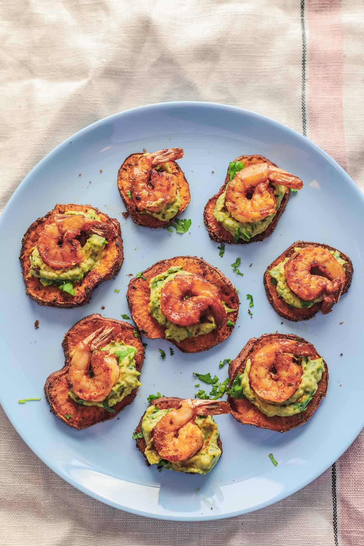 A plate of seven seafood appetizer bites on top of a white, black and pink kitchen towel