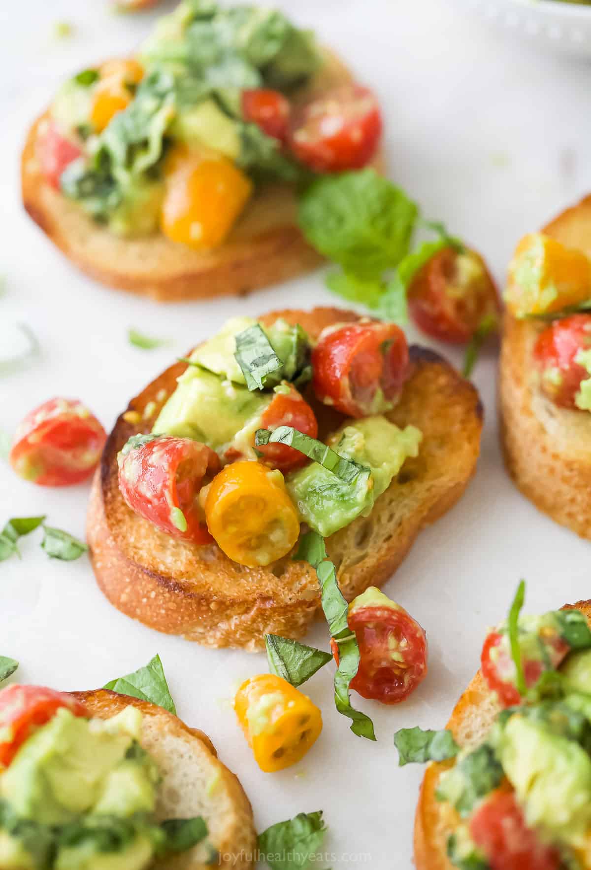 Crispy slices of French bread are toasted until golden, rubbed with garlic cloves, then finished off with a fresh avocado bruschetta topping! Toasted French bread topped with a tomato, basil and avocado mixture